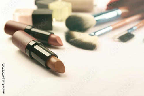 Makeup set with brushes and lipsticks on light background