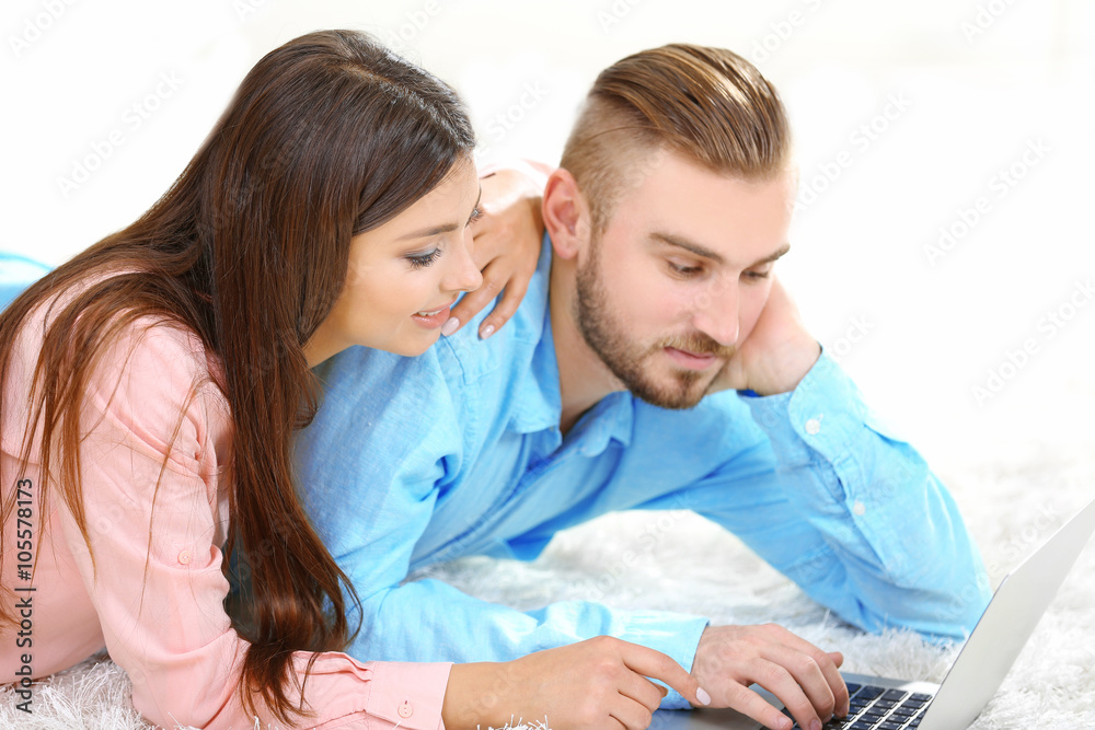 Happy couple lying on the floor and working on laptop Happy couple lying on the floor and working on laptop