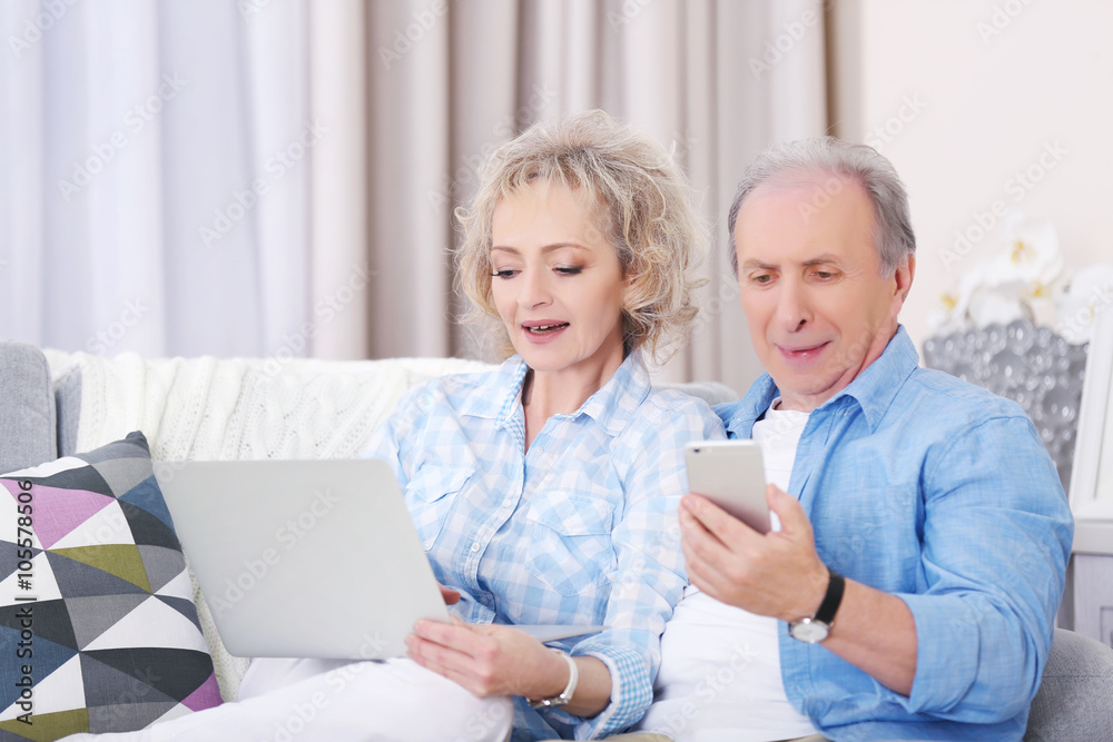 Mature couple using laptop and mobile phone at home Mature couple using laptop and mobile phone at home