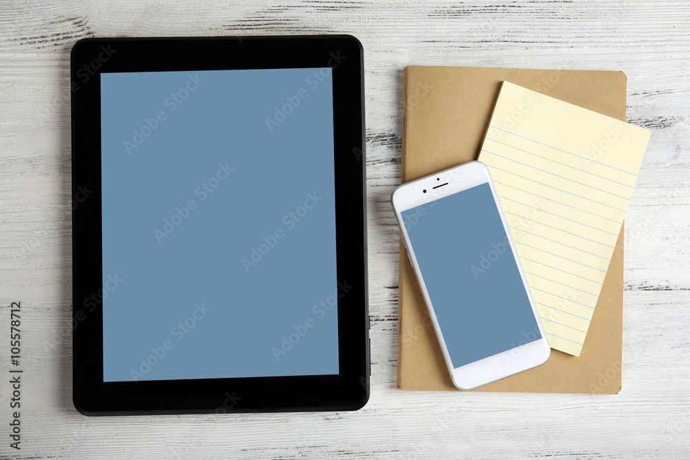 Modern mobile phone, tablet and notebook on white wooden background Modern mobile phone, tablet and notebook on white wooden background