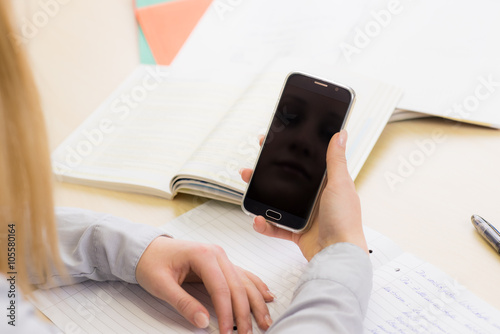 schülerin schaut unbemerkt auf das telefon im unterricht