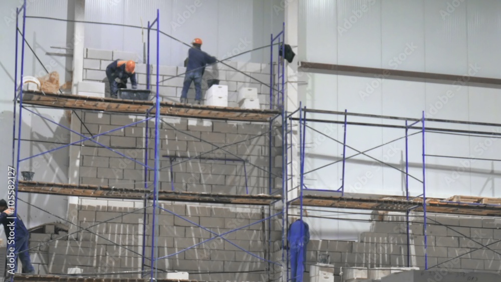 the workers on the scaffolding inside a large and modern warehouse the workers on the scaffolding inside a large and modern warehouse