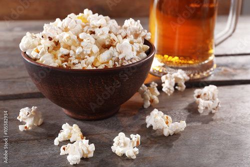 Glass mug of light beer with popcorn on wooden table, close up