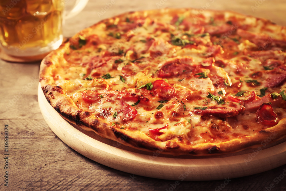 Delicious pizza  and glass of beer are on wooden table, close up