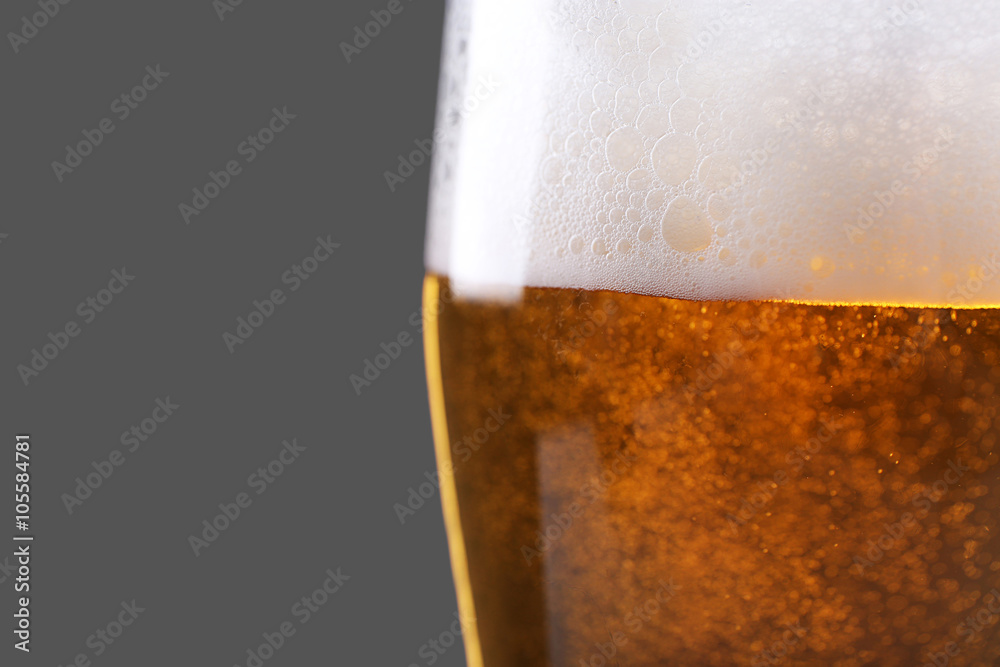 Glass of lager beer on grey background, close up
