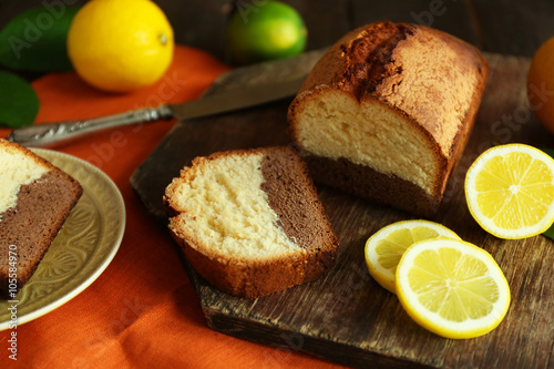 Delicious sweet cake bread with lemons on wooden cutting board closeup