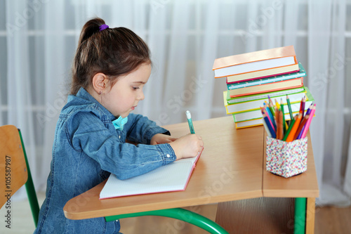 Little girl writing with pe...