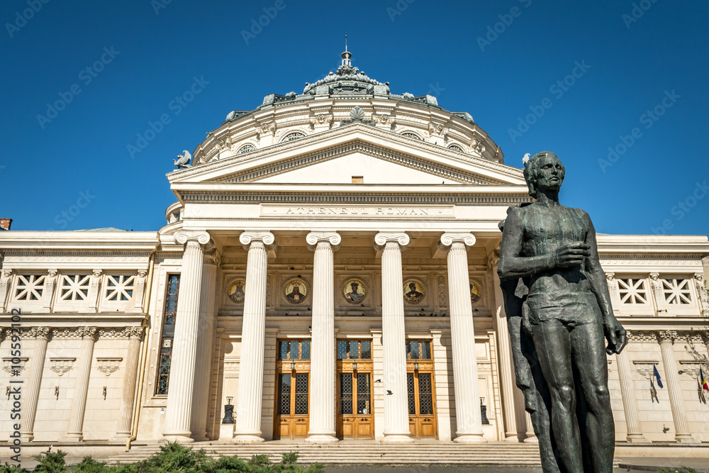 The statue of romanian national poet, Mihai Eminescu, placed in front of the iconic Ateneul Roman (Romanian Athenaeum), a symbol of the city of Bucharest, on a spring day