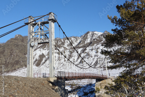 Suspension bridge Oroktoysky through the frozen Katun  river among mountains, Altai, Russia
 photo