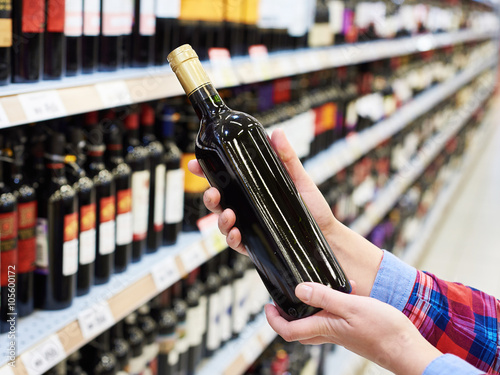 Woman with bottle of red wine in store