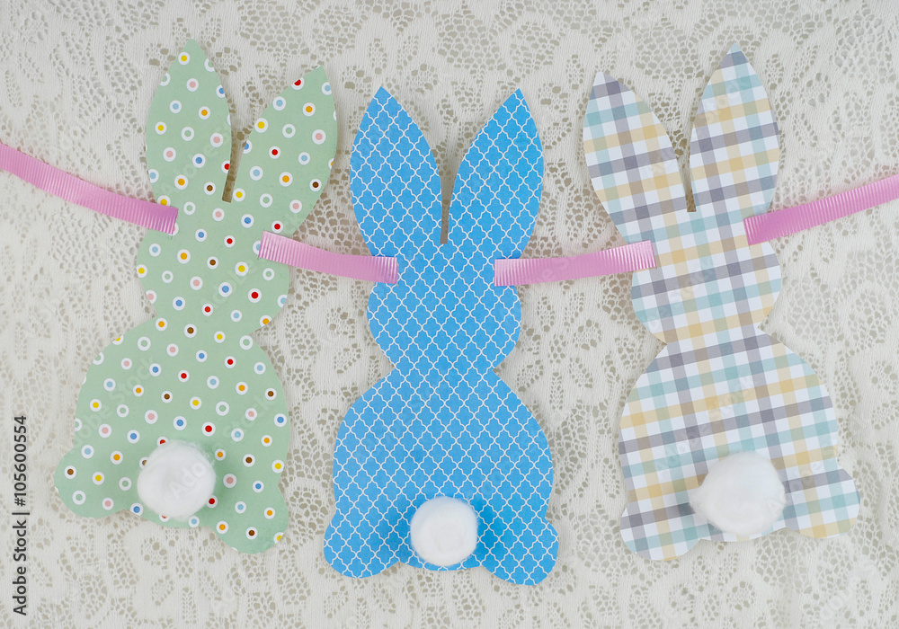 Cute craft paper cutout bunny shapes on natural background with cotton swab tails for Easter Cute craft paper cutout bunny shapes on natural background with cotton swab tails for Easter