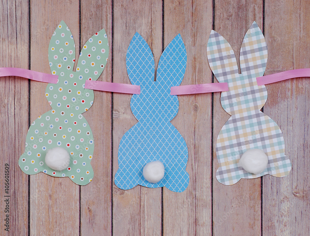 Cute craft paper cutout bunny shapes on natural background with cotton swab tails for Easter Cute craft paper cutout bunny shapes on natural background with cotton swab tails for Easter