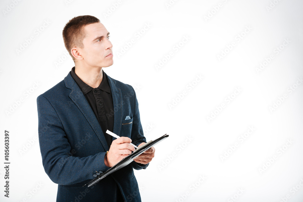 Pensive businessman holding clipboard and looking up