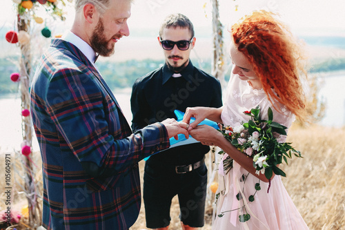Redhead bride puts the wedding ring to the groom