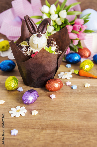 Easter cupcake and chocolate eggs on wooden background
