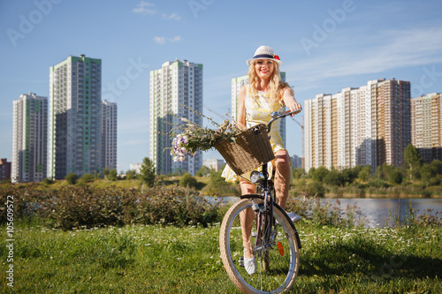 Beautiful sweet blonde woman walks with bicycle near skyscrapers