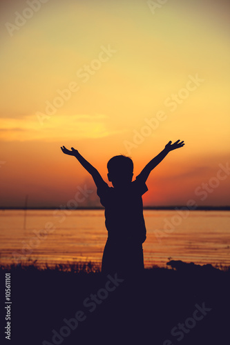 Silhouette of child enjoying the view at riverside.