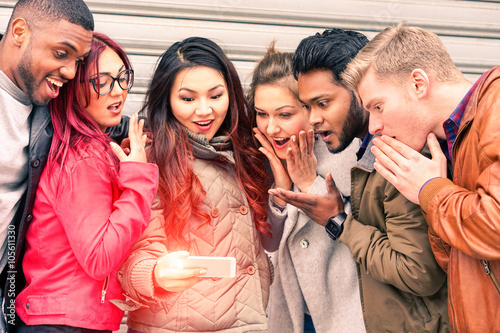 Multiracial group of young friends surprised face looking mobile phone new miracles technology - Mixed race best friendship and astonished facial expression concept - Main focus Indian man at right 