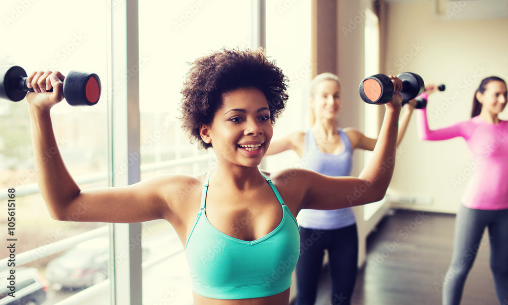 group of happy women with dumbbells in gym group of happy women with dumbbells in gym