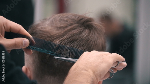 Barber cuts the hair of the client with scissors at a barber shop