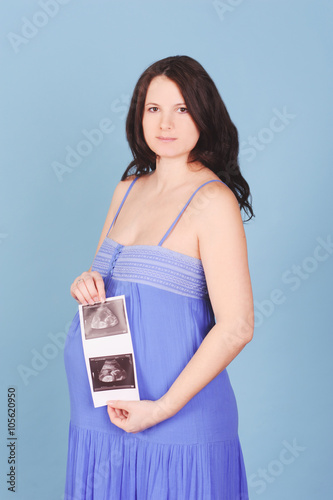 Pregnant woman holding x-ray of tummy with baby