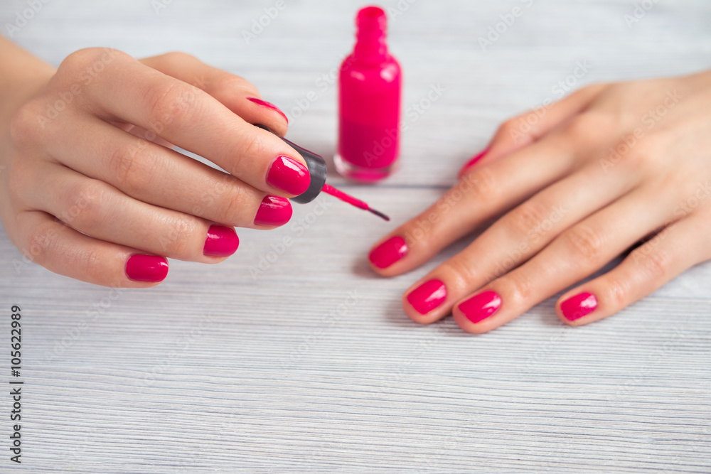 Woman paints her nails pink polish, close-up Woman paints her nails pink polish, close-up