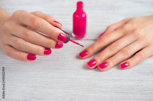 Woman paints her nails pink polish  close-up