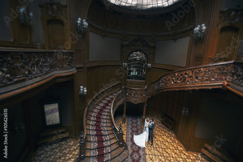 Fairytale newlywed couple hugging in wooden theatre hall