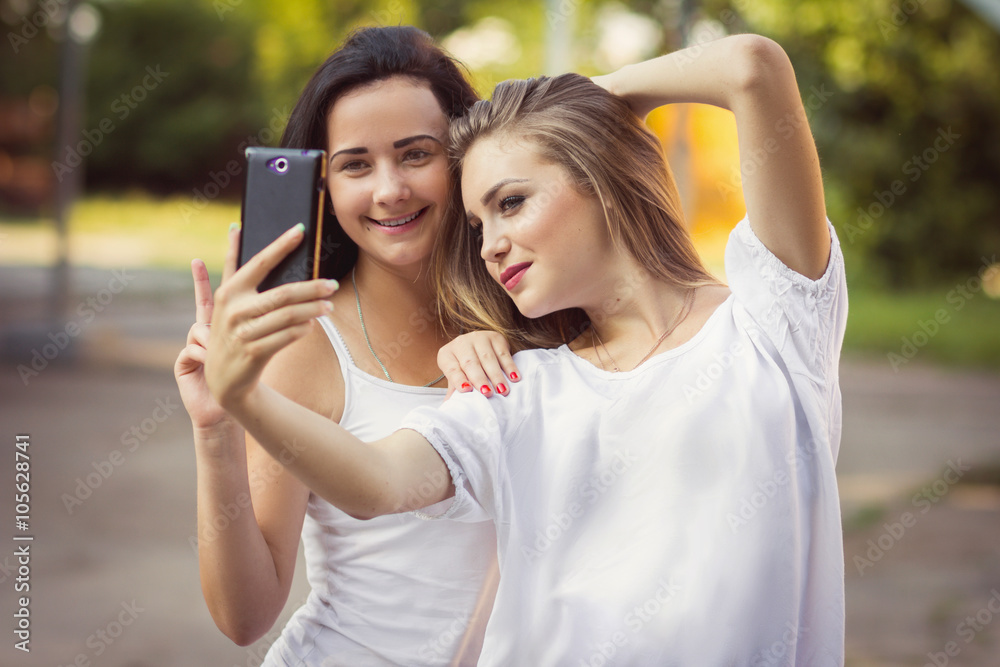 girlfriends taking a selfie in urban city context. Concept of friendship and fun with new trends and technology. Best friends eternalizing the moment with modern smartphone