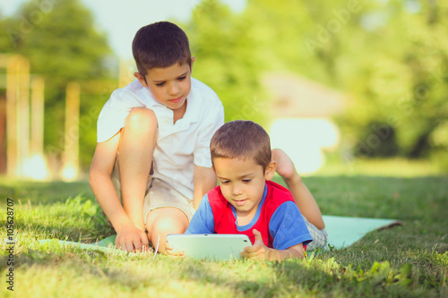 two handsome boys work with pad outdoors