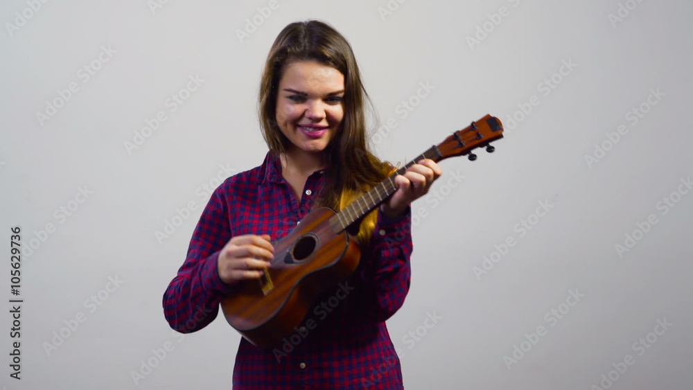 young girl playing ukulele in front of white wall young girl playing ukulele in front of white wall
