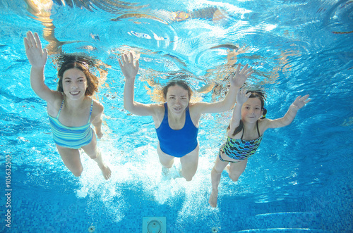 Family swims in pool or sea under water, happy active mother and children have fun underwater, kids sport on family vacation
