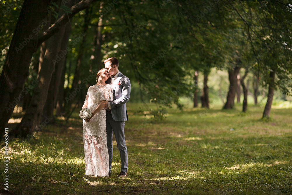 Fototapeta premium Bride and groom walking away in summer park outdoors