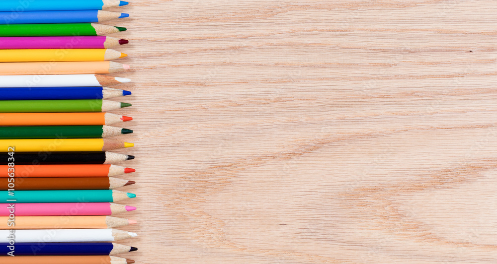 Colorful pencils lined up on oak wooden desktop Colorful pencils lined up on oak wooden desktop
