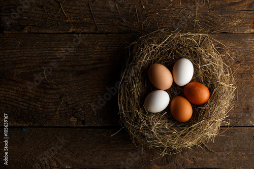 Chicken eggs in a nest on a wooden rustic background