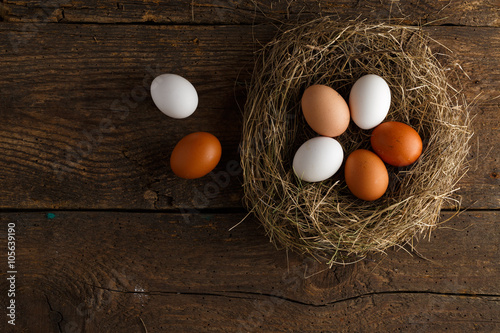 Chicken eggs in a nest on a wooden rustic background