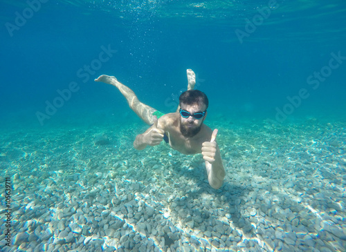 Beard man with mask diving in a blue clean water