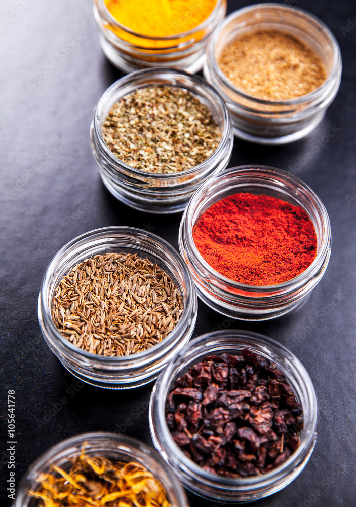 Spices on black background in special jars. Food