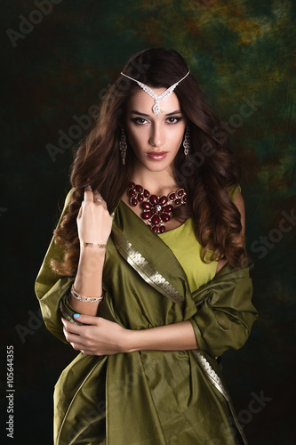 Beautiful woman in green indian sari  and jewelry on colorful ba
