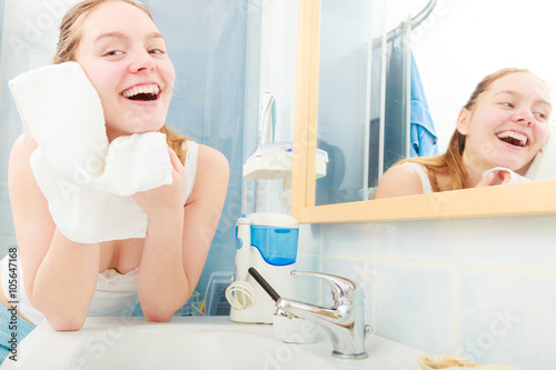 woman washing her face with clean water in bathroom