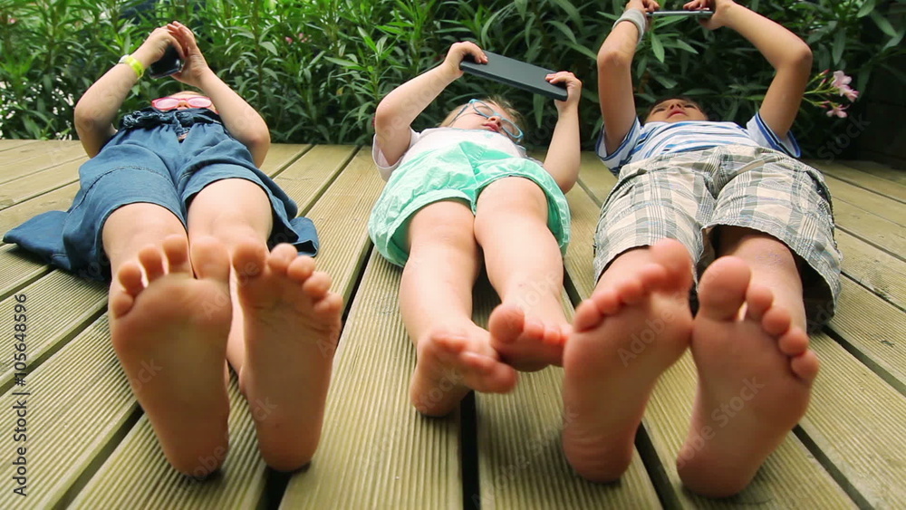 Baby foot close up. Children playing with electronic gadgets on the wooden floor