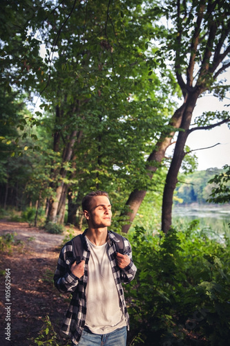 Portrait of young handsome man with backpack wanderer walk in the woods