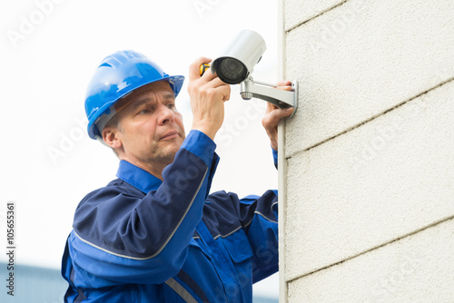Male Technician Fixing CCTV Camera On Wall