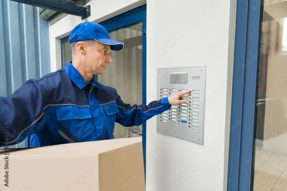 Delivery Man Pressing Button Of Intercom To Enter Building Delivery Man Pressing Button Of Intercom To Enter Building