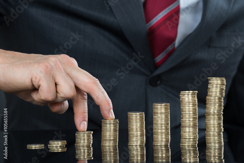 Close-up Of Businessman Fingers Walking On Pile Of Coins