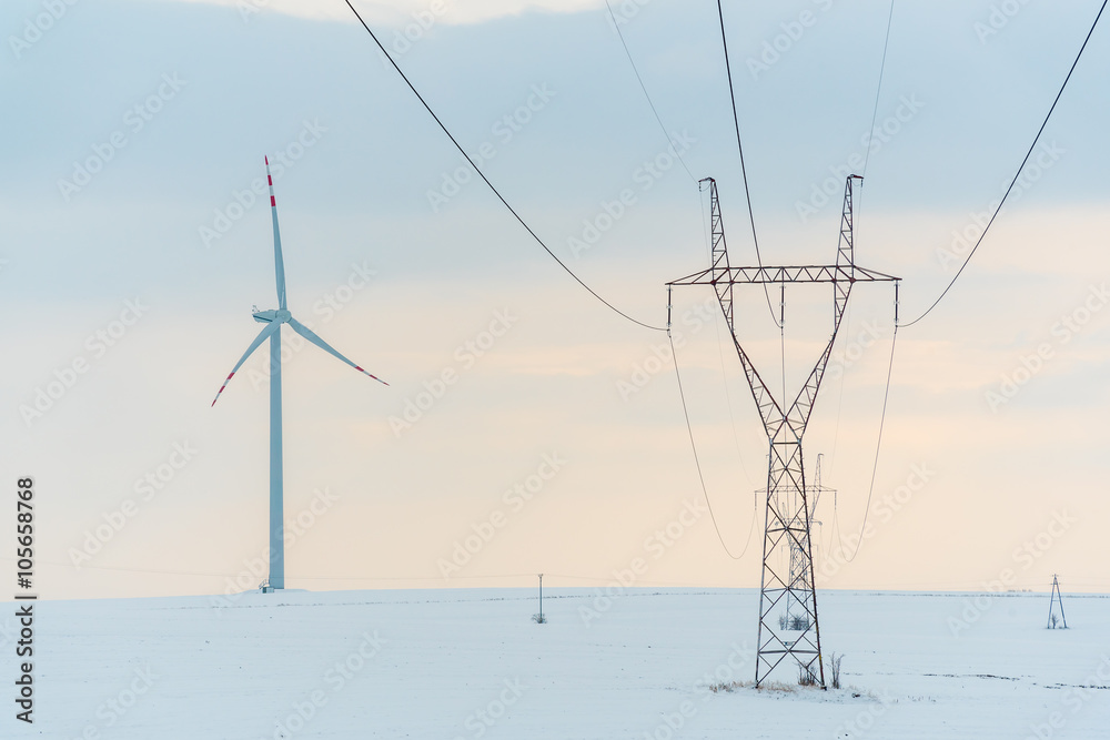 Windmill and powerlines on the field in winter