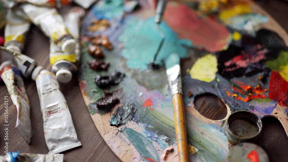 Closeup of paintbrush in woman hands mixing paints on palette