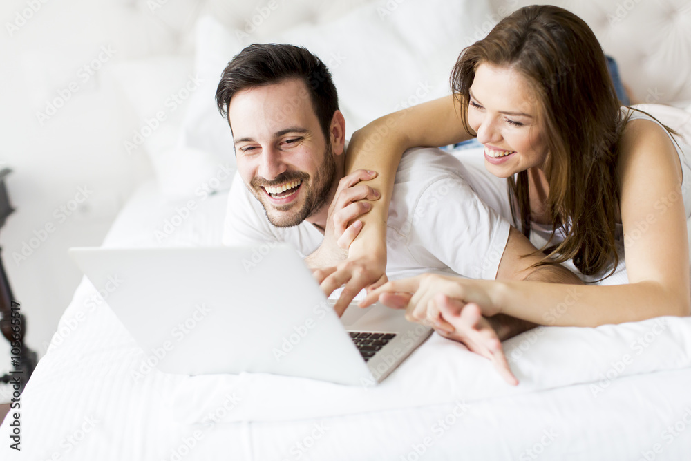 Young couple with laptop in the bed Young couple with laptop in the bed