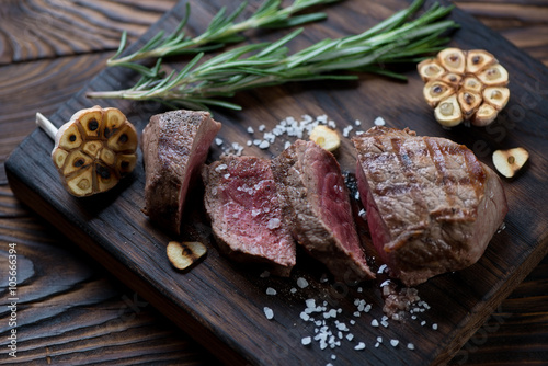 Sliced medium rare grilled asado steak on a wooden serving board