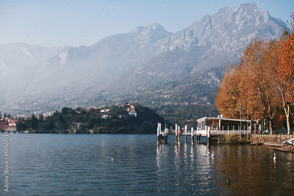 Fototapeta premium Pier and autumn trees on the shore of a mountain lake Como
